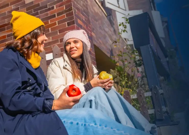 Two people enjoying food choices outside.