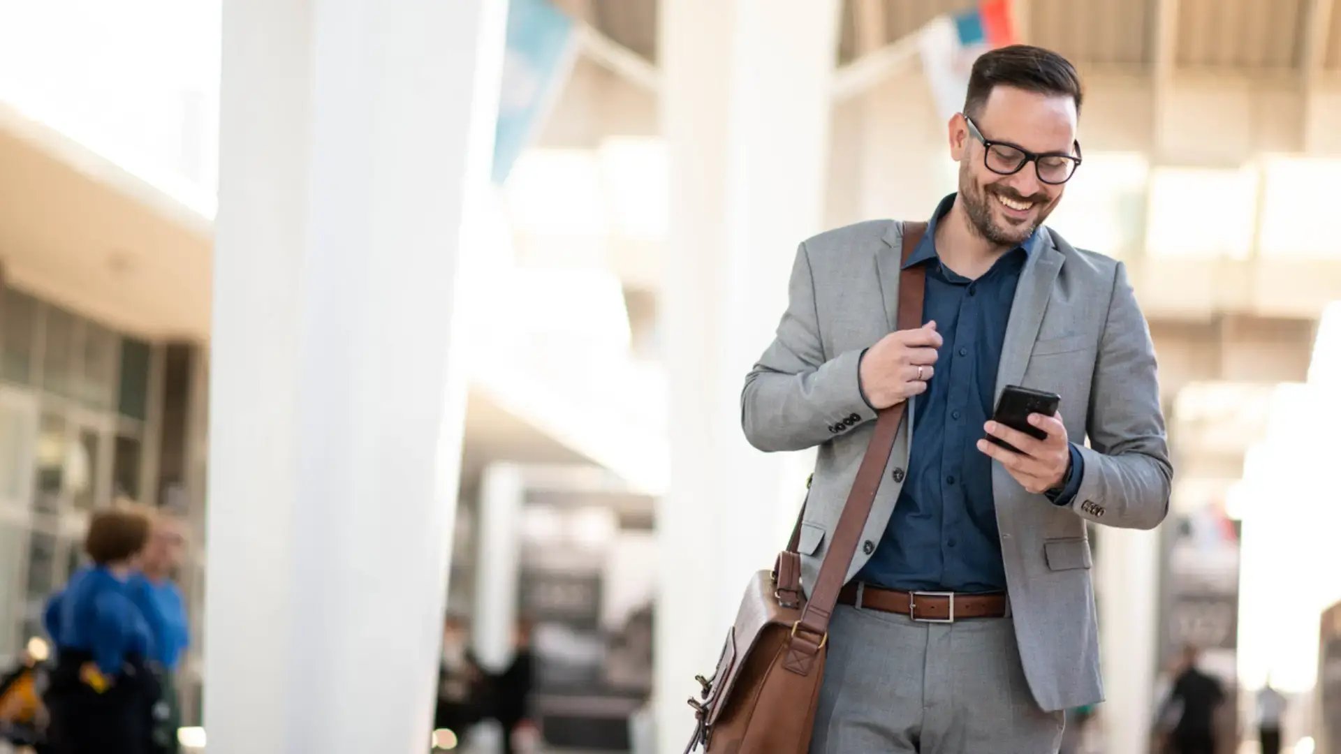 man in a bus station receiving a gift card on his phone and smiling