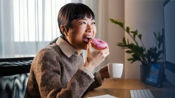 woman looking at her desktop screen and eating a tim hortons 
