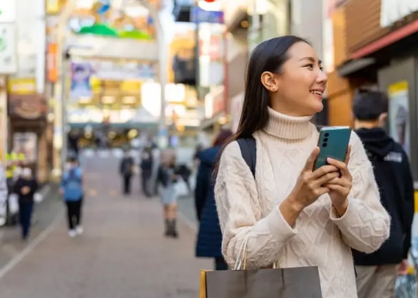 young woman receiving a gift card in her phone while walking in a big city